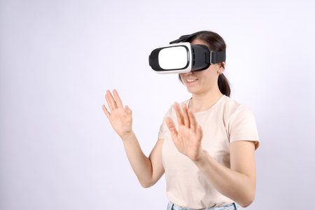 A woman wearing a white shirt is wearing a virtual reality headset and is making a fist. Concept of...