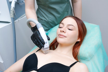 A woman is getting a facial treatment. woman is smiling and relaxed. woman is wearing a black braの写真素材