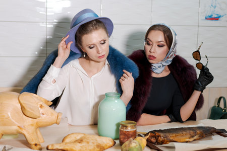 Two women are sitting at a table. One of the women is wearing a hat and the other is wearing sunglassesの写真素材