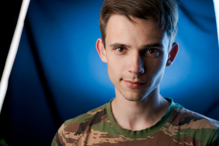 A young man with brown hair and a green and brown striped shirt. He is smiling.の写真素材