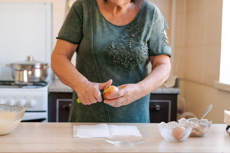 Woman is cutting an onion on a table. She is wearing a green shirt