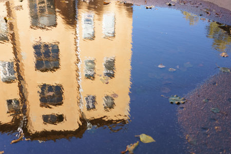 Building is reflected in a puddle of water. The reflection of the building is blurry and distortedの写真素材