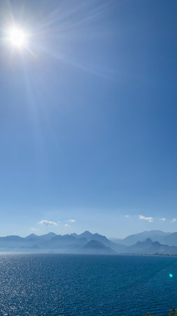 Clear blue sky with mountains in the background. The sun is shining brightly, creating a beautiful and serene atmosphereの写真素材