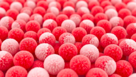 Close up of many red and pink fuzzy balls. The balls are arranged in a pattern and appear to be soft and fluffy. Concept of warmth and comfort, as if the balls are inviting and cozyの素材