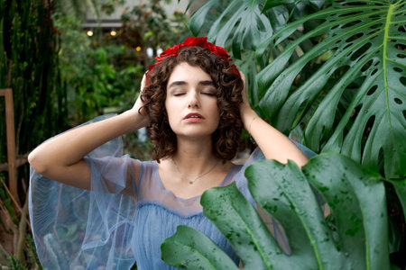 Woman wearing a blue dress and a red flower headband. She is looking at the cameraの写真素材