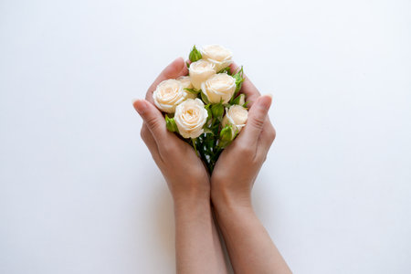 Women's hands hold a bouquet of white roses on a light background, creating an atmosphere of purity and elegance.の写真素材