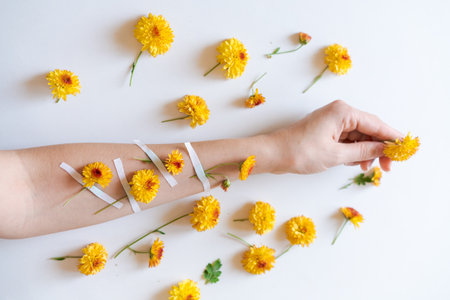 A hand with yellow flowers attached with ribbons on a white background. The flowers are neatly arranged around, creating a bright and delicate compositionの写真素材