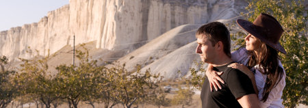 Man and woman are standing on a hillside. The man is wearing a black shirt and the woman is wearing a brown hatの写真素材