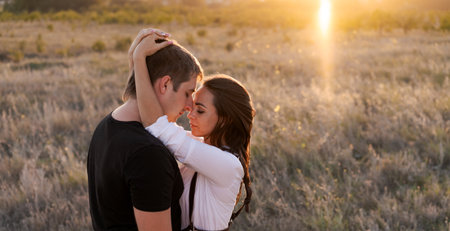 Man and a woman are hugging in a field. The man is wearing a black shirt