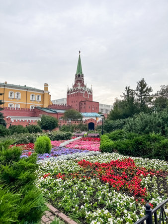 Large building with a green spire sits in front of a garden. The garden is filled with flowers of various colors, including red, purple, and yellowの写真素材