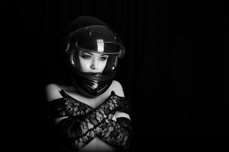 Woman wearing a helmet and gloves. She is looking at the camera. The helmet is black and the gloves are black laceの写真素材