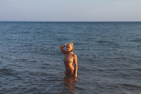 Woman in a bikini is standing in the ocean. She is wearing a black and white bikini
