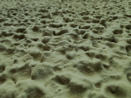 Wall with a textured surface. The texture is made of small rocks. The wall is yellow in colorの写真素材