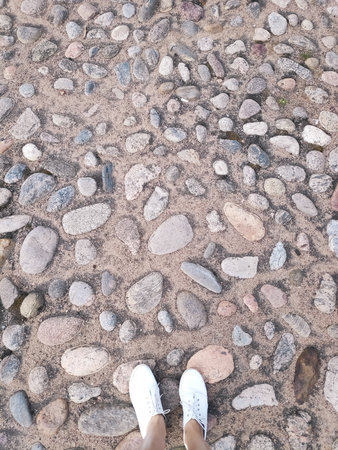Person is standing on a rocky surface. The person is wearing white shoes. The surface is made of rocksの写真素材