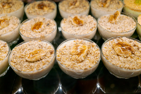 Row of small bowls filled with a dessert made with nuts and bananas. The bowls are lined up on a tableの写真素材