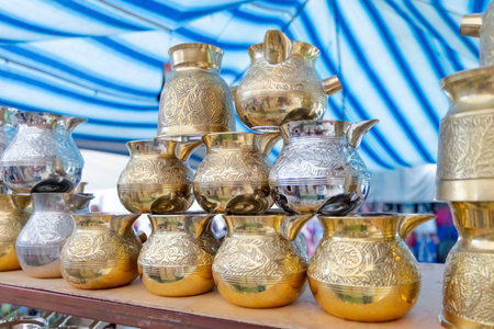 Stack of gold and silver pitchers. Some are tall and some are short. They are on a tableの写真素材