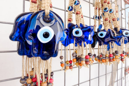 Row of blue and black beads hang from a wire. The beads are in the shape of a hand with a blue eyeの写真素材