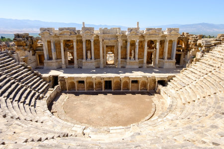Large stone building with a large open courtyard. The courtyard is surrounded by stone steps. There are several statues in the courtyardの写真素材
