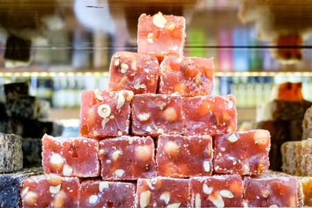 Stack of red candies with nuts on top. The candies are piled on top of each otherの写真素材