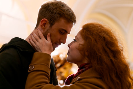 Man and a woman are kissing. The woman has red hair. The man is wearing a black jacketの写真素材