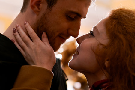 Man and a woman are kissing. The man is wearing a black shirt. The woman has red hair