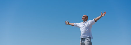 Man is standing in the air with his arms outstretched. He is wearing a white shirt and gray shorts