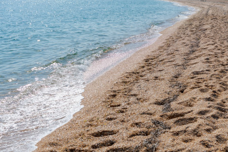 The beach is covered in sand and has a small body of water. The water is calm and the sand is dryの写真素材