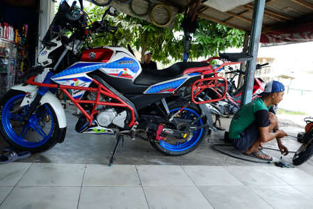 Lampung, Indonesia, March 13, 2022: An Asian man works as a repair shop mechanic repairing motorbikesのeditorial素材