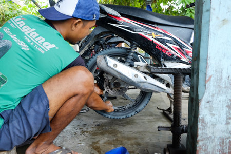 Lampung, Indonesia, March 13, 2022: An Asian man works as a repair shop mechanic repairing motorbikesのeditorial素材