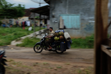 Lampung, Indonesia, March 11, 2022: Blurred motion of a man riding a motorbike carrying gas cylindersのeditorial素材