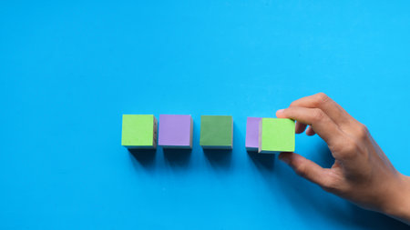 Hands choosing colorful wooden blocks isolated on light blue background, positive thinking