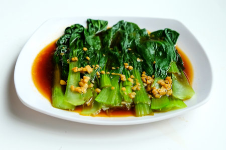 Chinese dish serving on white plate, Bok choy or baby chinese cabbage with oyster sauce and garlic on white backgroundの写真素材