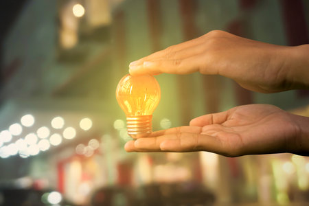 Hand-holding light bulb with city light bokeh as background