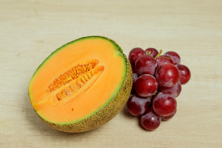 Slice of melon and bunch of grapes on table, top view