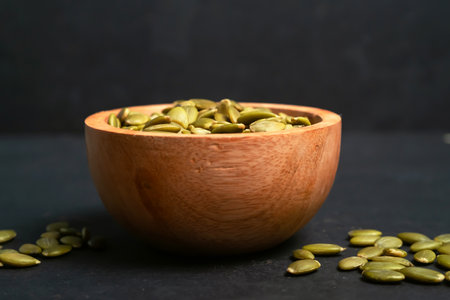 Pumpkin seeds in a wooden bowl on a black background.の写真素材