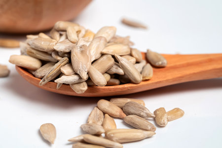 Sunflower seeds in wooden spoon isolated on white backgroundの写真素材
