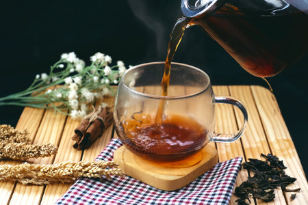 Pouring tea into a cup on a wooden table, close upの写真素材