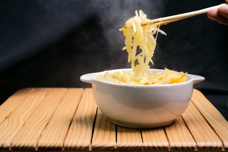 Sauteed young papaya with hot chili peppers in a white bowl on a wooden table. Traditional dishes from Indonesiaの写真素材