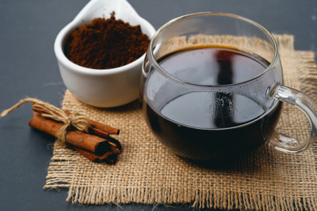 Coffee in a glass cup and cinnamon on a black backgroundの写真素材