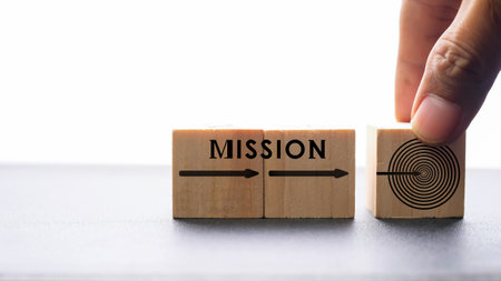 Businessman's hand puts a wooden cube with the word mission.の写真素材