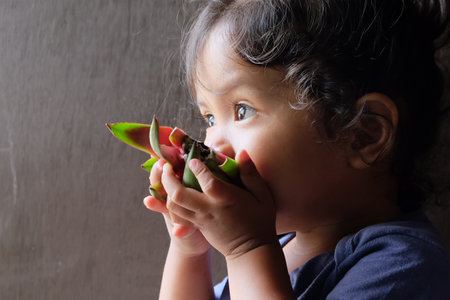 Cute little baby girl eating a dragon fruit. Selective focus.の写真素材