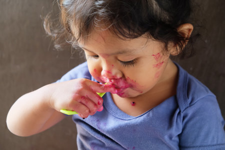 Portrait of a cute Asian baby eating a strawberry from a spoon.の写真素材
