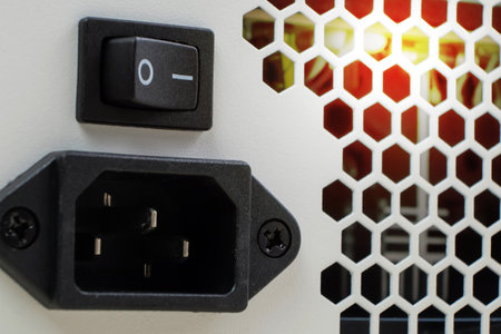 Close up of black electric plug on white wall with sunlight in backgroundの写真素材