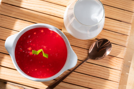 Red borscht in a white bowl and spoon on wooden tableの写真素材