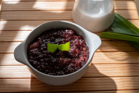 Black sticky rice porridge with coconut milk sauce served in a white bowl. Indonesian traditional dessertの写真素材