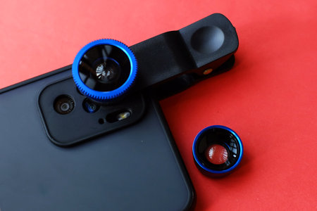 Smartphone with a blue lens on a red background close-upの写真素材