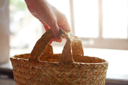 Hand holding a wicker basket with natural light in the morning.の写真素材