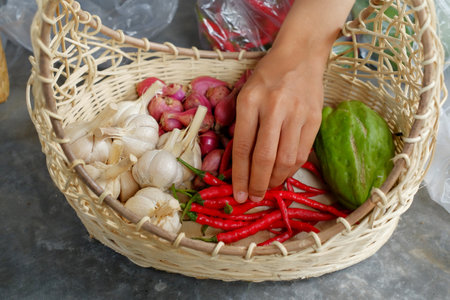 Asian woman holding basket of fresh vegetables for cooking in the market.の写真素材