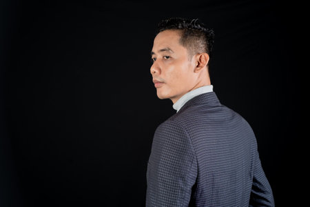 Portrait of a handsome Asian business man on black background with copy spaceの写真素材
