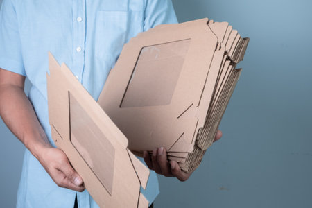Man holding cardboard box on grey background, delivery and transportation concept.の写真素材